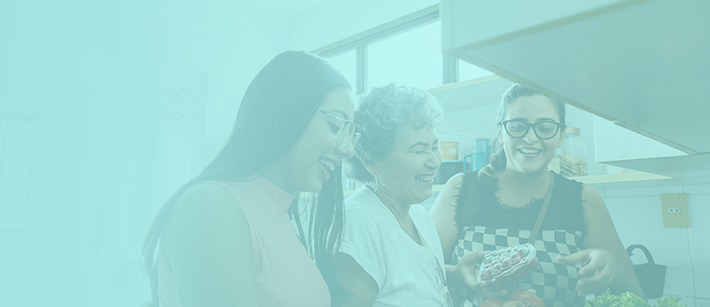 Grupo de mujeres riendo mientras seleccionan verduras en una cocina.